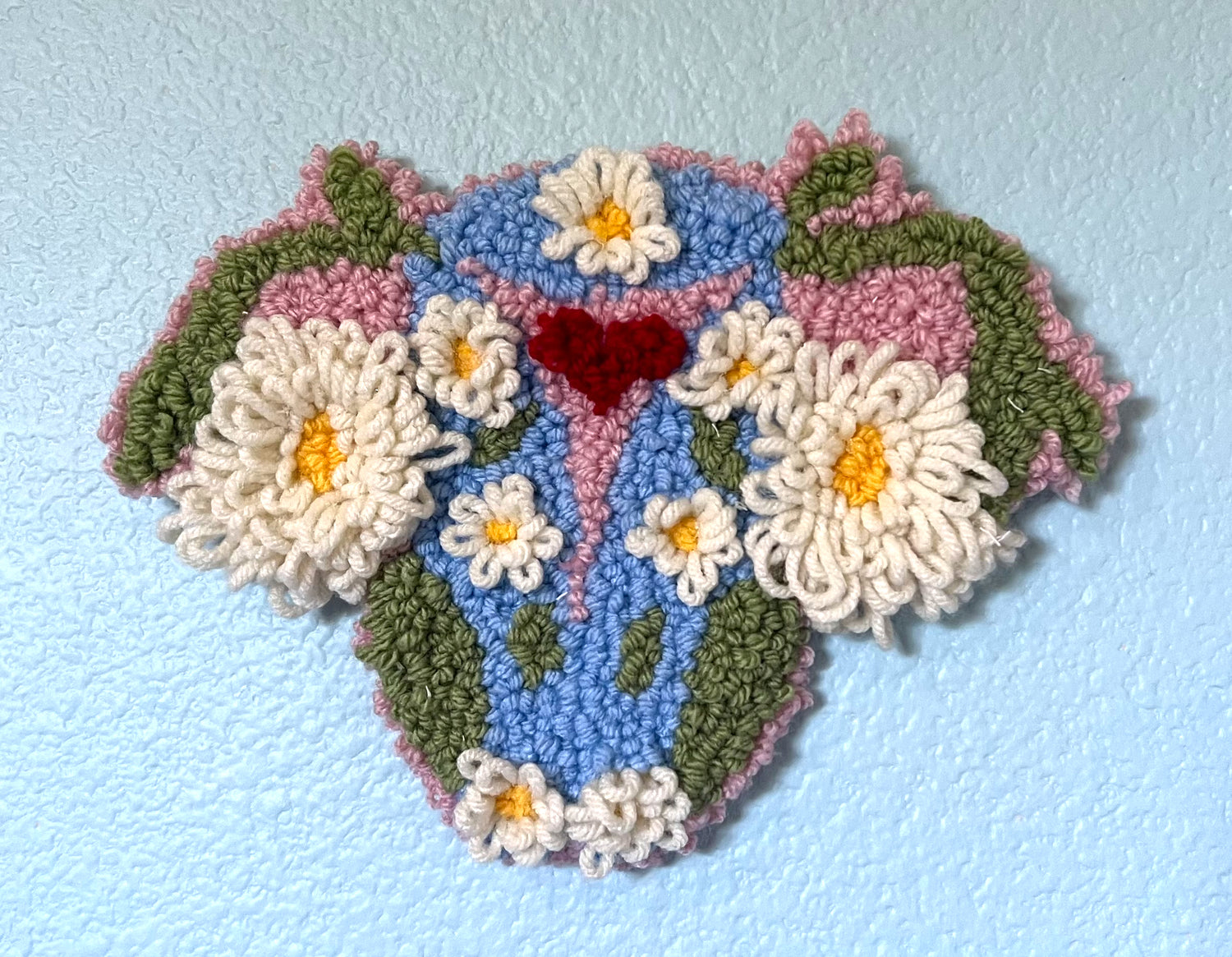 tufted wall wall hanging of a uterus made up of flowers and plants